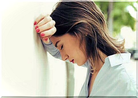 Stressed woman with her head against the wall