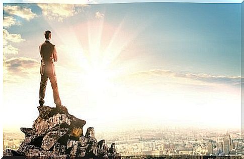 Man looks at the city from a rock